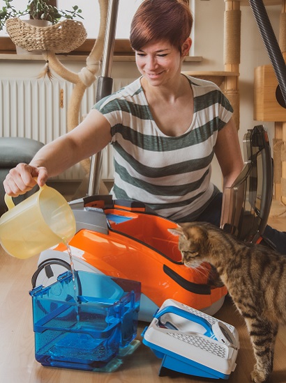 Woman filling AQUA filter box with water while cat watching