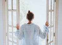 Woman breathing fresh air on open window